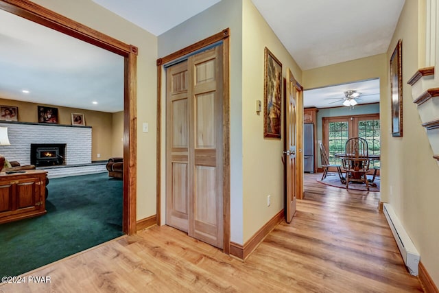 hall with light hardwood / wood-style flooring and a baseboard heating unit