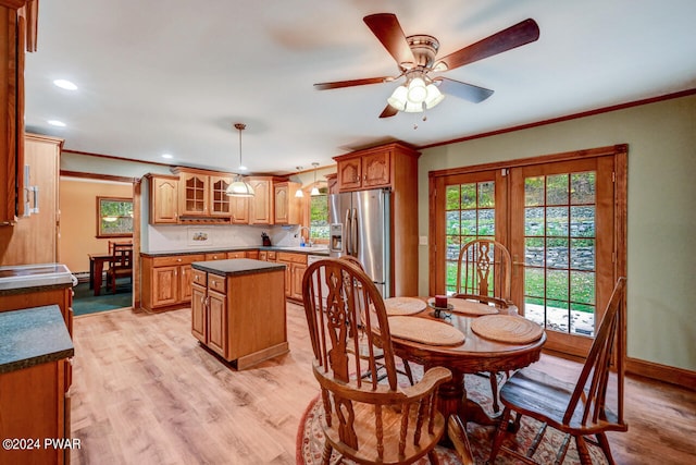 dining area featuring light wood-type flooring, ceiling fan, ornamental molding, and sink