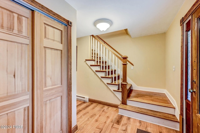 foyer entrance with baseboard heating and light hardwood / wood-style floors