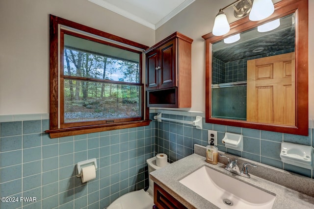 bathroom with vanity, a shower with door, toilet, ornamental molding, and tile walls