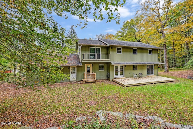 back of house featuring french doors, a balcony, a lawn, and a wooden deck