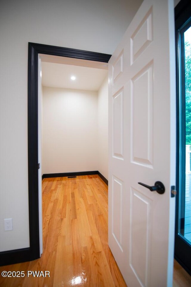 hall with baseboards and light wood-style floors