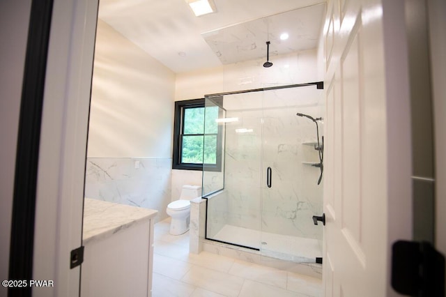 full bath with vanity, a marble finish shower, wainscoting, tile walls, and toilet