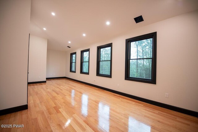 unfurnished room featuring recessed lighting, a healthy amount of sunlight, light wood-type flooring, and baseboards