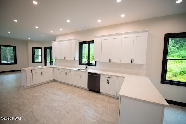 kitchen featuring a sink, white cabinetry, a peninsula, decorative backsplash, and dishwasher