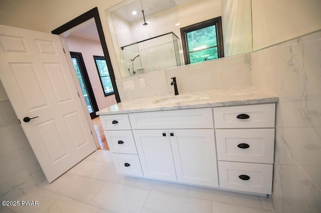 bathroom featuring a marble finish shower, vanity, and tile walls