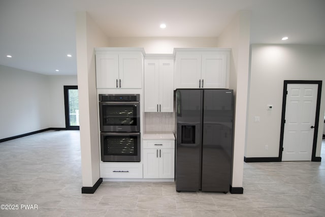 kitchen with baseboards, white cabinetry, double oven, tasteful backsplash, and black fridge