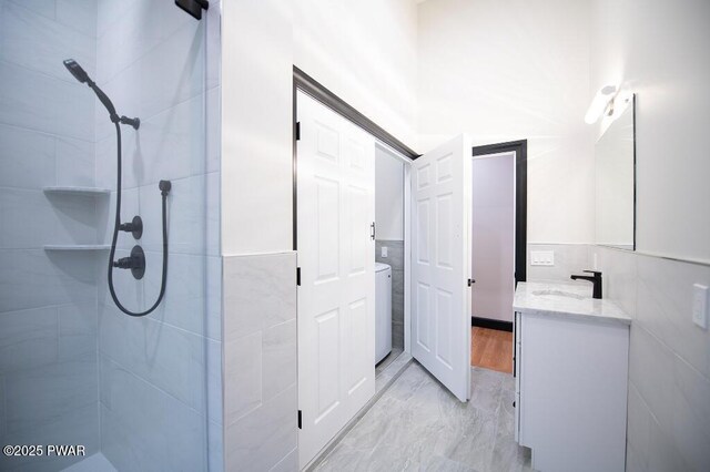 full bath with vanity, tile walls, washer / clothes dryer, and tiled shower