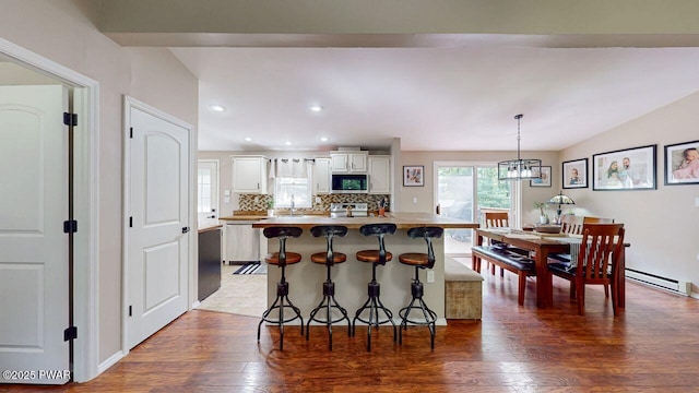 142 Myck Rd, Dingmans Ferry, PA 18328 - kitchen with stainless steel appliances, a kitchen bar, wood finished floors, decorative backsplash, and white cabinetry