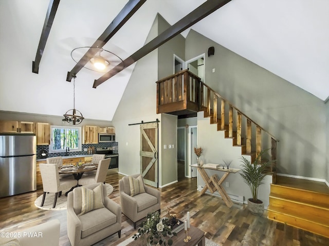 living room with dark wood-type flooring, sink, a barn door, an inviting chandelier, and high vaulted ceiling