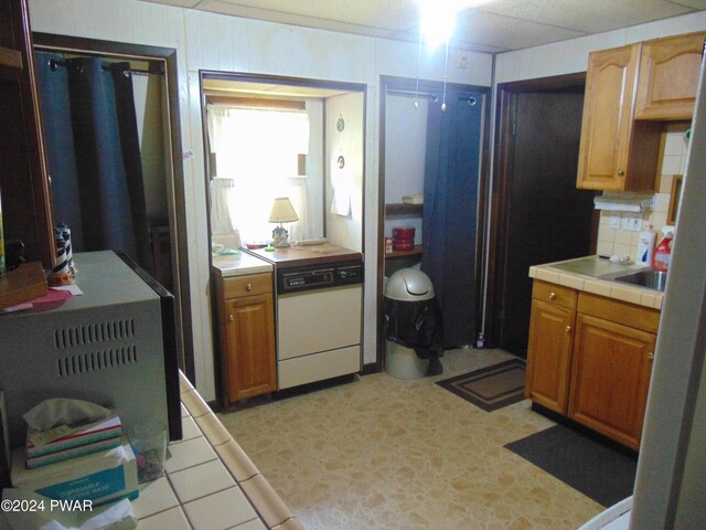 kitchen with decorative backsplash, tile countertops, and white dishwasher