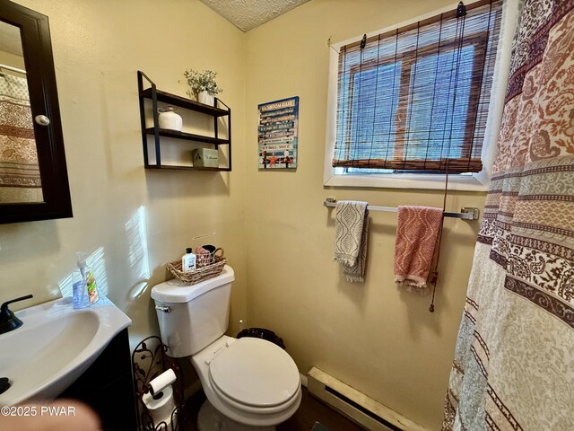 bathroom with a baseboard radiator, toilet, and a textured ceiling