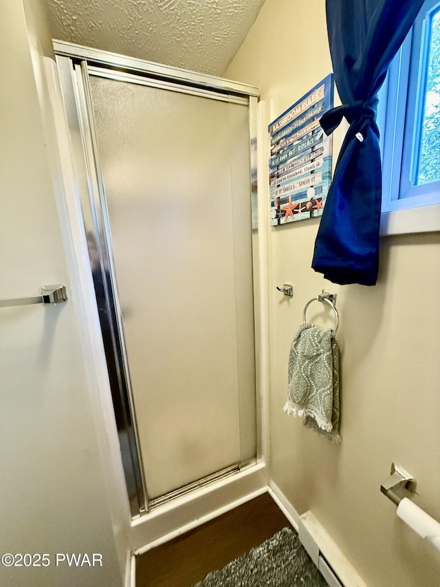 bathroom with a shower with shower door, a baseboard radiator, and a textured ceiling