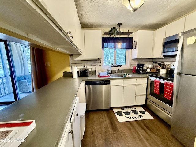 kitchen featuring sink, appliances with stainless steel finishes, dark hardwood / wood-style floors, white cabinets, and decorative backsplash