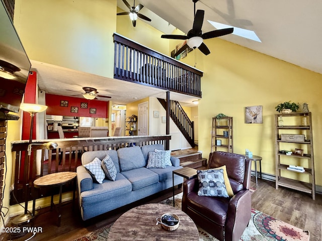 living room with high vaulted ceiling, dark wood-type flooring, ceiling fan, and a skylight