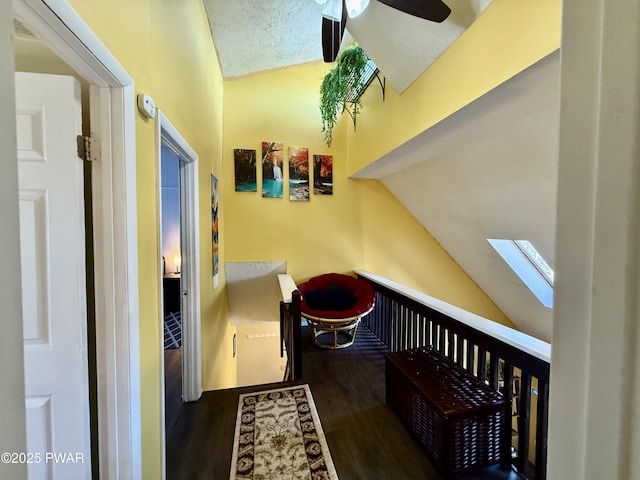 hallway featuring dark hardwood / wood-style flooring, a textured ceiling, and vaulted ceiling with skylight