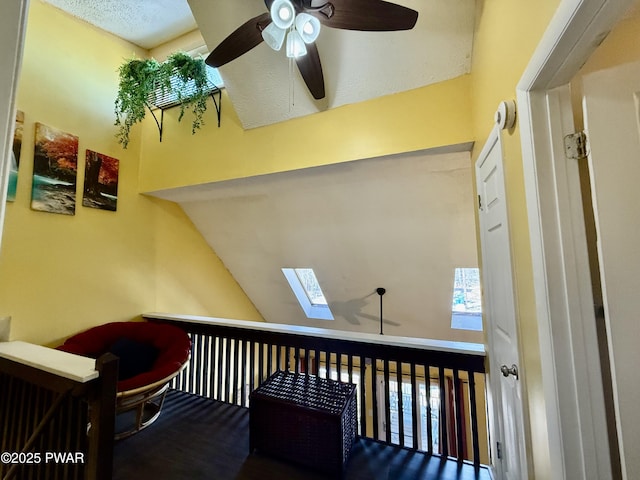 stairway featuring lofted ceiling with skylight and ceiling fan