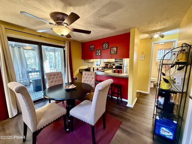 dining space with ceiling fan, a textured ceiling, and dark hardwood / wood-style flooring