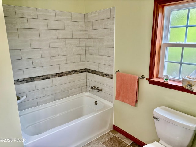 bathroom featuring toilet, baseboards, and shower / bathing tub combination
