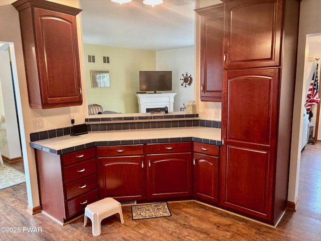 kitchen featuring dark brown cabinets, tile counters, dark wood-style floors, and visible vents