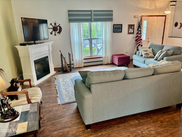 living area with a glass covered fireplace, a baseboard heating unit, and dark wood-style floors