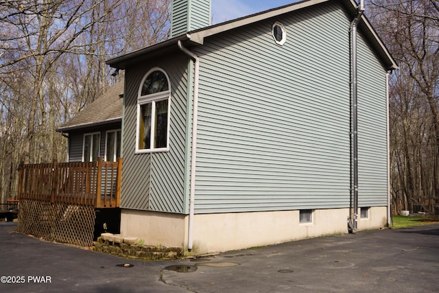 view of side of property featuring a chimney and a deck