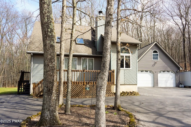 view of front of house featuring aphalt driveway, a chimney, roof with shingles, and a garage