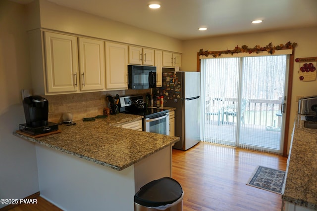 kitchen featuring stainless steel appliances, light wood-style flooring, a peninsula, tasteful backsplash, and white cabinetry