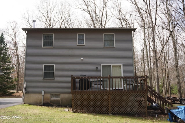 rear view of house with a yard, stairway, and a deck