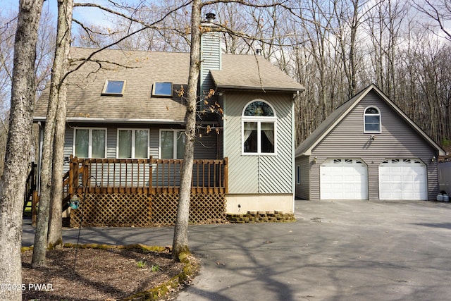 view of front of house featuring a chimney, a detached garage, roof with shingles, and aphalt driveway