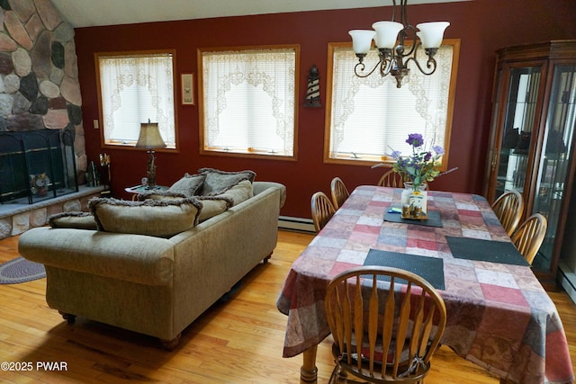dining space featuring a wealth of natural light, an inviting chandelier, light wood-style floors, and a baseboard radiator
