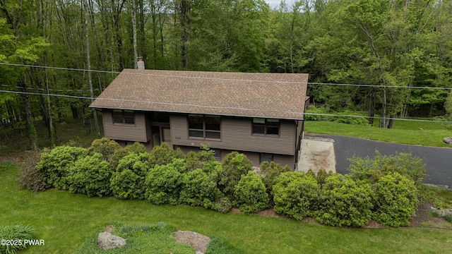 1111 Advent Rd, Lake Ariel, PA 18436 - bi-level home featuring a wooded view, a front lawn, a chimney, and roof with shingles