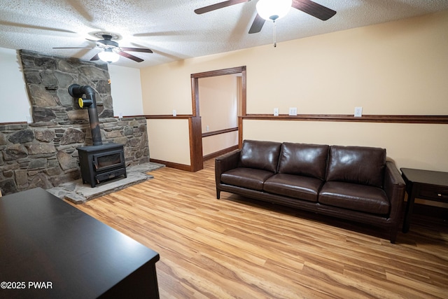 1111 Advent Rd, Lake Ariel, PA 18436 - living room with a ceiling fan, wood finished floors, a wood stove, a textured ceiling, and baseboards