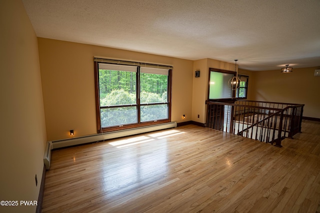 1111 Advent Rd, Lake Ariel, PA 18436 - spare room featuring a chandelier, wood finished floors, a baseboard heating unit, baseboards, and a textured ceiling
