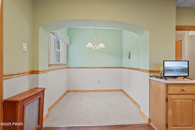 132 Dundaff St, Forest City, PA 18421 - unfurnished dining area with a chandelier, arched walkways, wood finished floors, and carpet floors