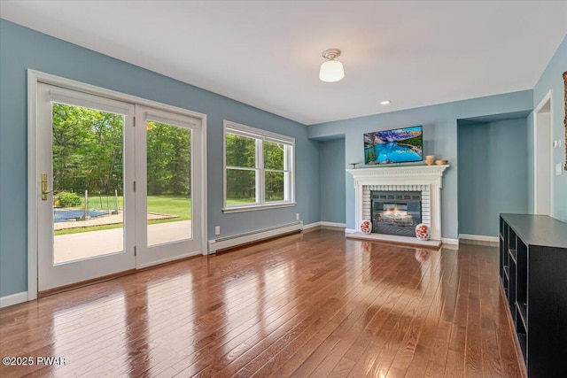 174 Lee Rd, Shohola, PA 18458 - unfurnished living room with a baseboard radiator, a brick fireplace, hardwood / wood-style flooring, and baseboards