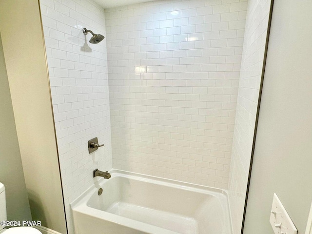 bathroom featuring tiled shower / bath combo and toilet