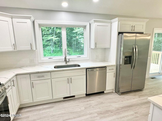 kitchen with stainless steel appliances, tasteful backsplash, sink, and white cabinets