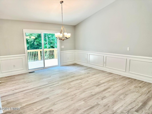 empty room featuring a notable chandelier and light hardwood / wood-style flooring