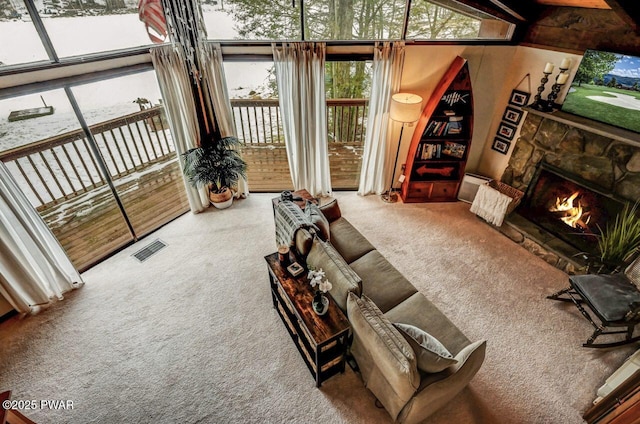 living room featuring a stone fireplace and carpet flooring