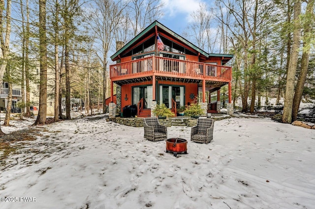 snow covered house featuring a deck and an outdoor fire pit