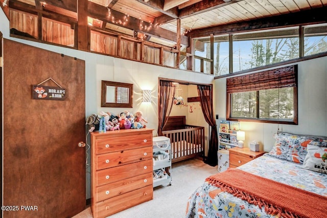 carpeted bedroom with beam ceiling, a high ceiling, and wood ceiling