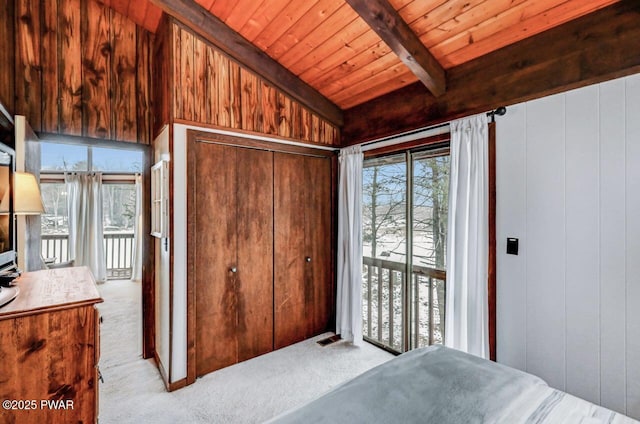 carpeted bedroom featuring wooden walls, lofted ceiling with beams, access to outside, wooden ceiling, and a closet