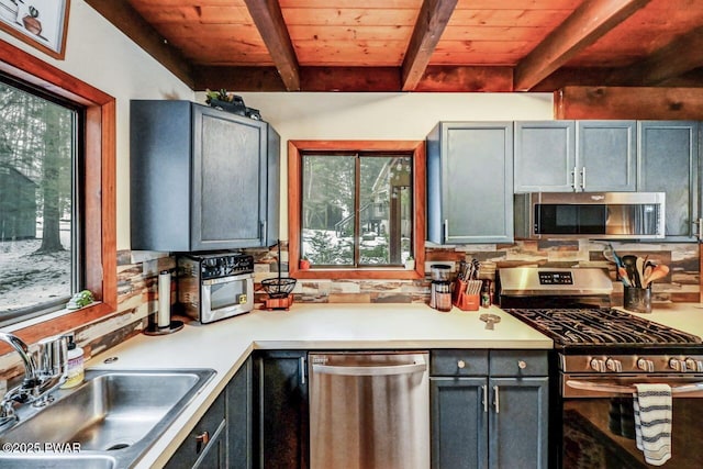 kitchen with beamed ceiling, appliances with stainless steel finishes, sink, and wooden ceiling