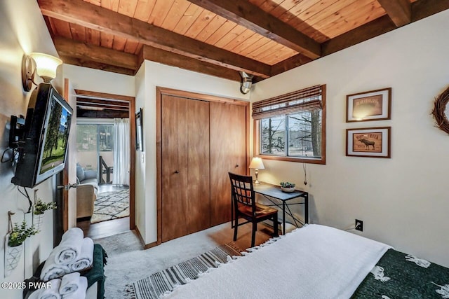 carpeted bedroom with beam ceiling, wood ceiling, and a closet