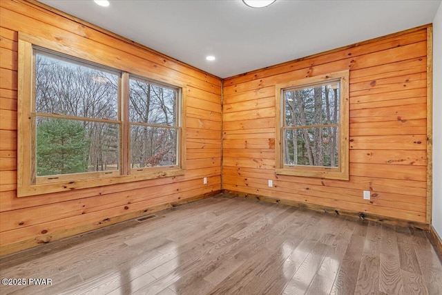 spare room with wood-type flooring and wooden walls