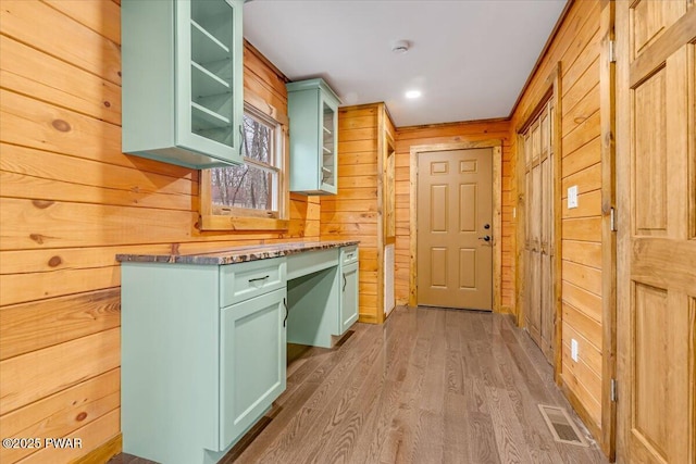 kitchen featuring hardwood / wood-style flooring, wood walls, and green cabinets