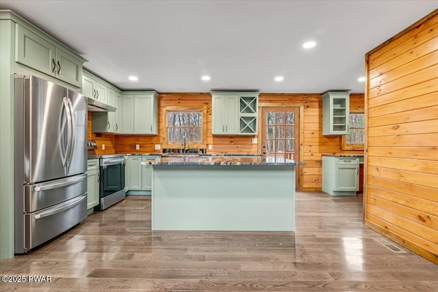 kitchen with wood walls, stainless steel appliances, and green cabinetry