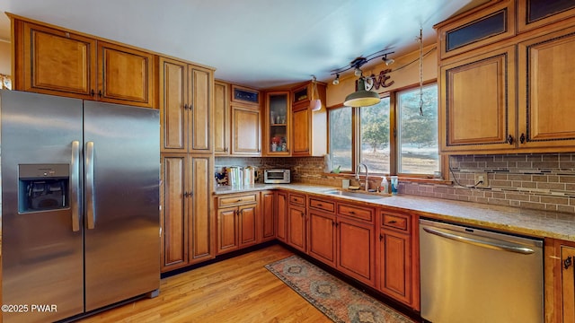 kitchen with light countertops, light wood-style flooring, appliances with stainless steel finishes, brown cabinetry, and a sink