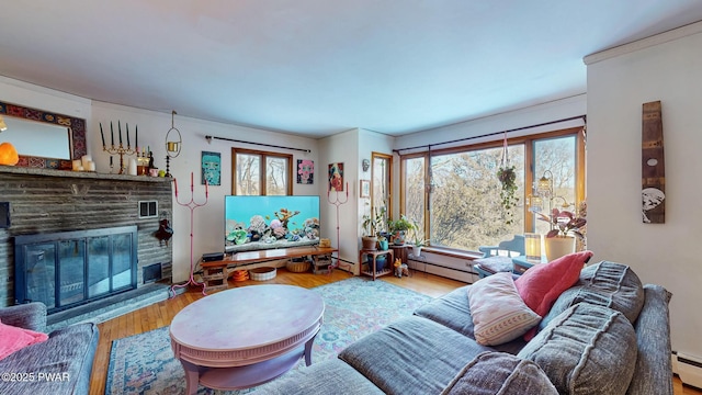 living area with light wood-type flooring, a baseboard radiator, a fireplace, and a baseboard heating unit